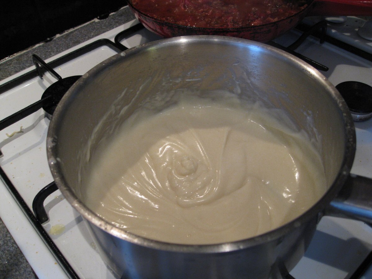 Helle Béchamelsauce wird in einem Topf mit dem Schneebesen gerührt