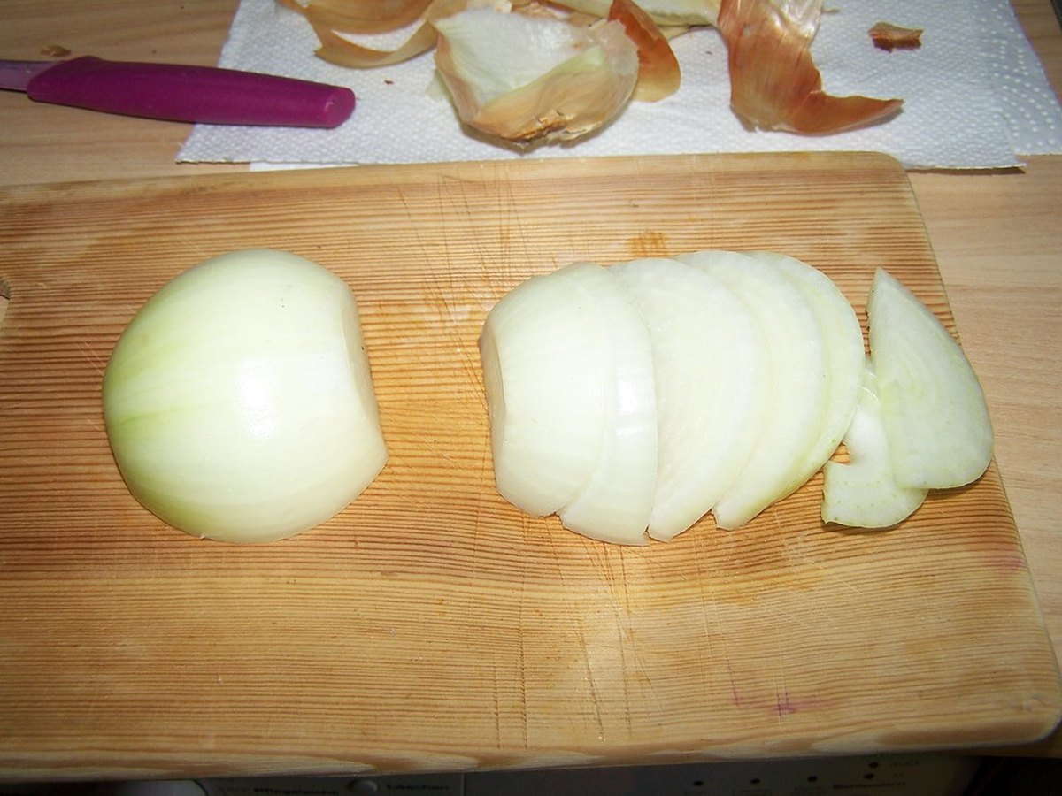 Eine Zwiebel wird auf einem Brett geschnitten