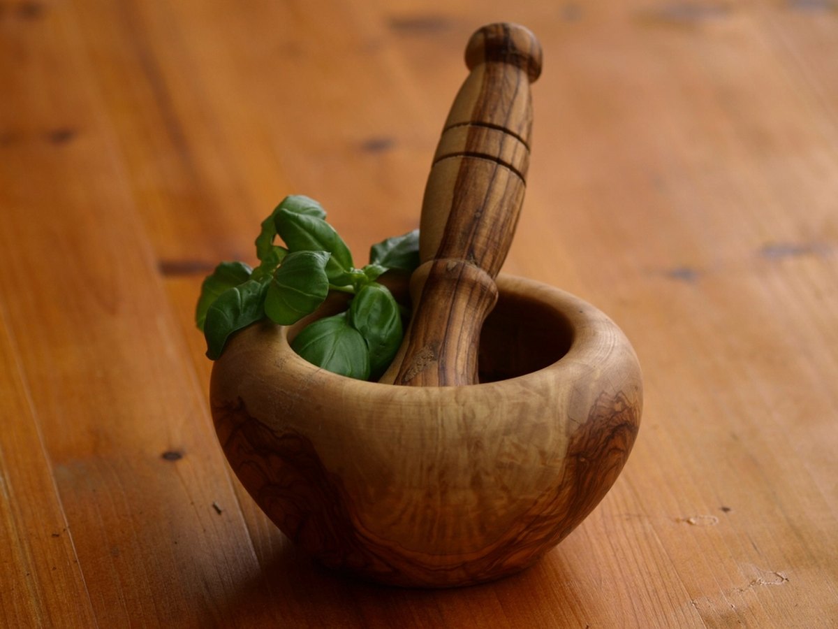 Mörser mit grünen Kräutern und Stößel