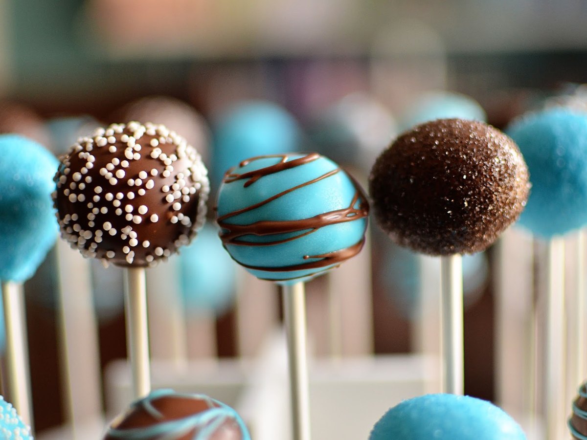 Fertige Cake Pops in Blau und Braun mit sichtbaren Stielen
