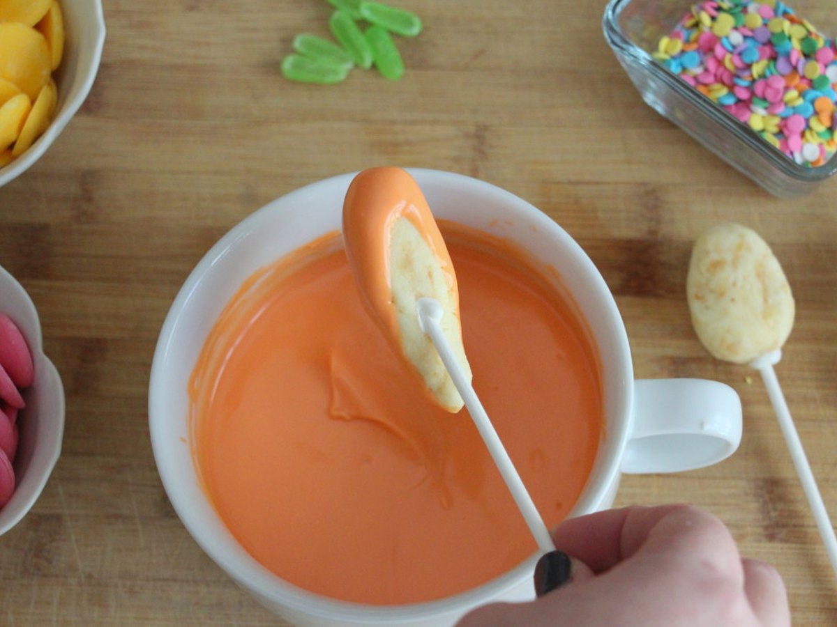 Ein Cake Pop wird in Schokolade getaucht