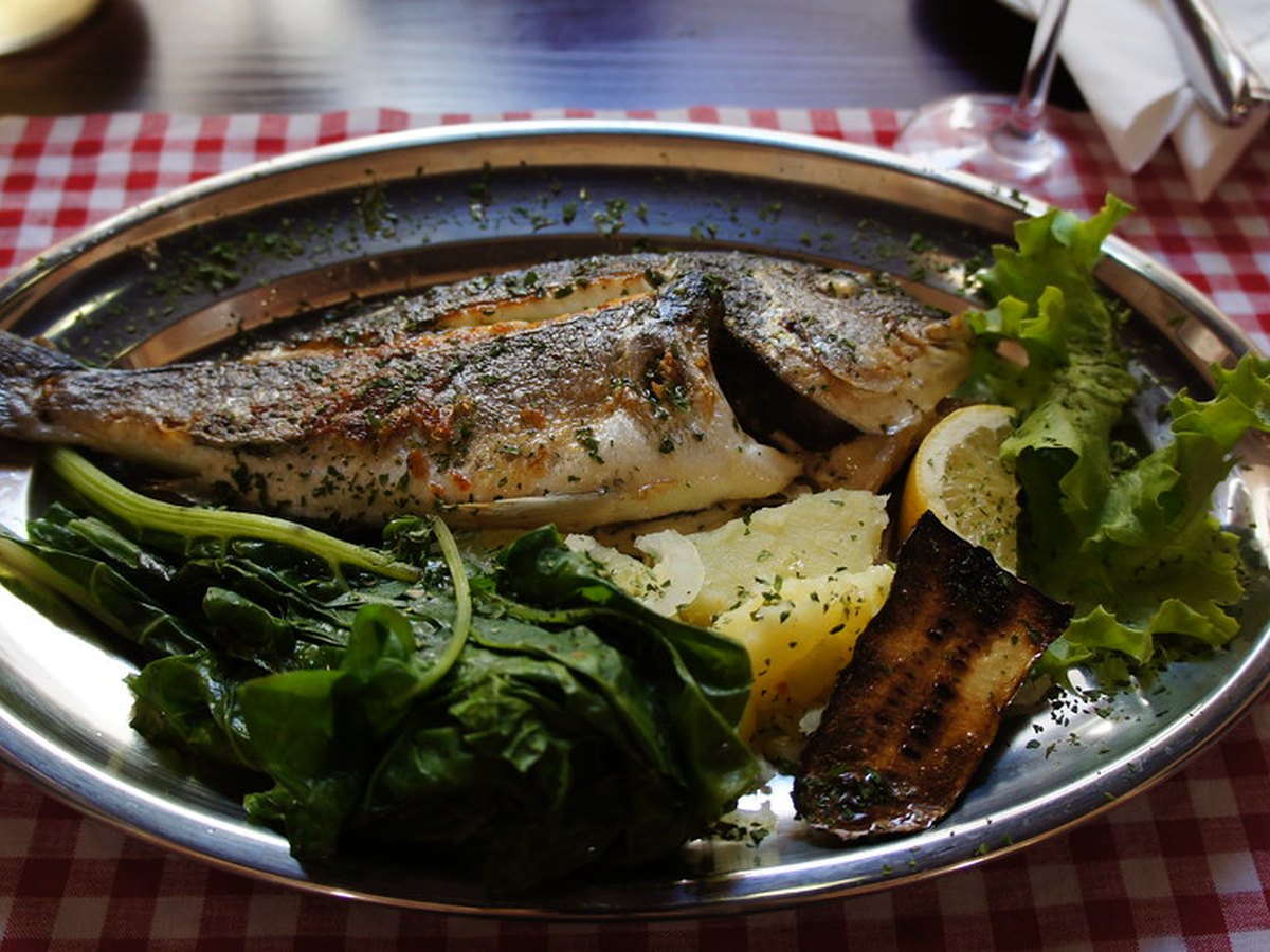 Gegrillte Forelle auf einem Teller mit Zitrone angerichtet