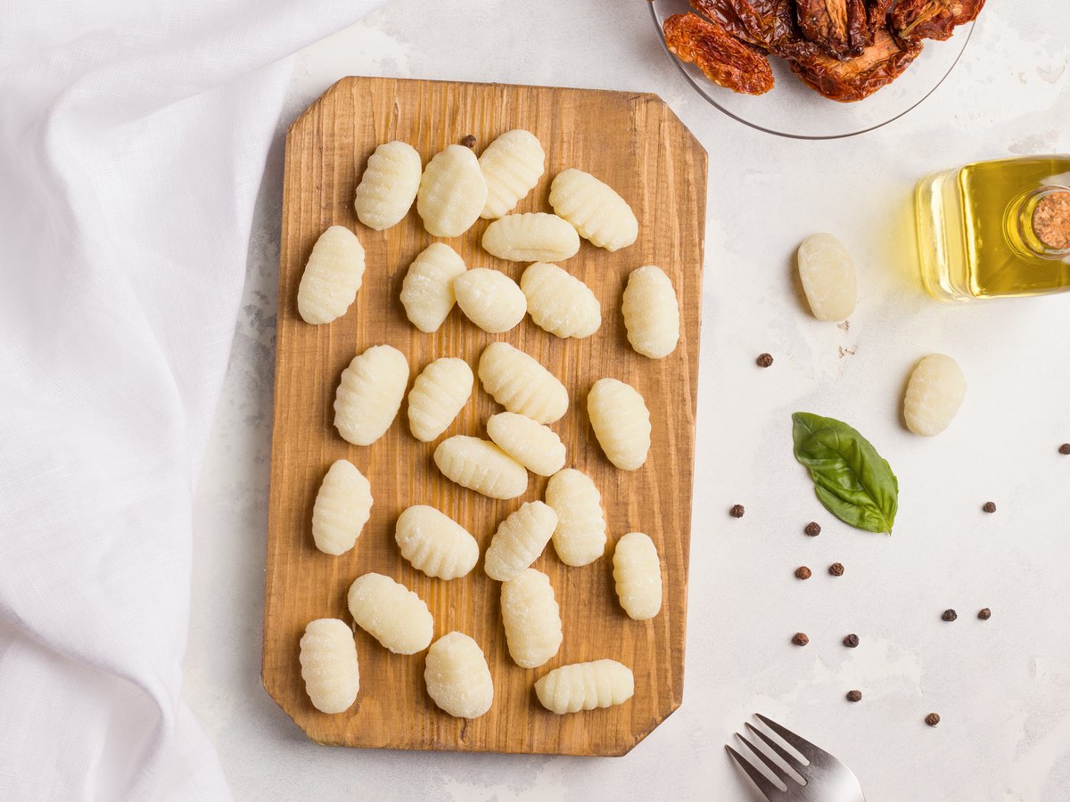 Gnocchi auf einem Holzbrett neben Gewürzen