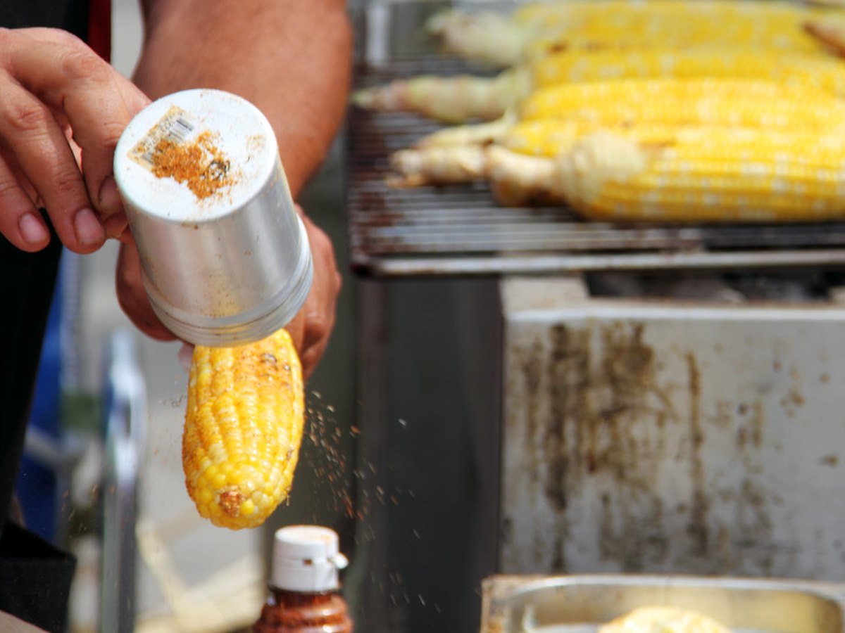 Gegrillter Maiskolben wird gewürzt