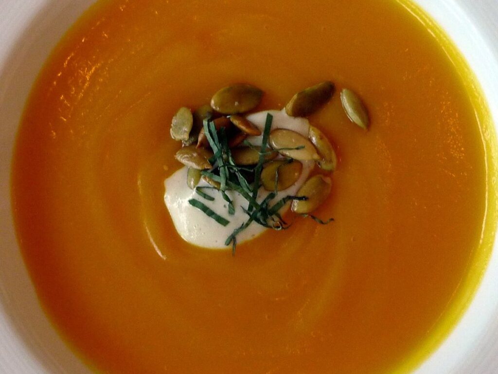 Orangefarbene Karotten-Ingwer-Suppe mit Sahneklecks