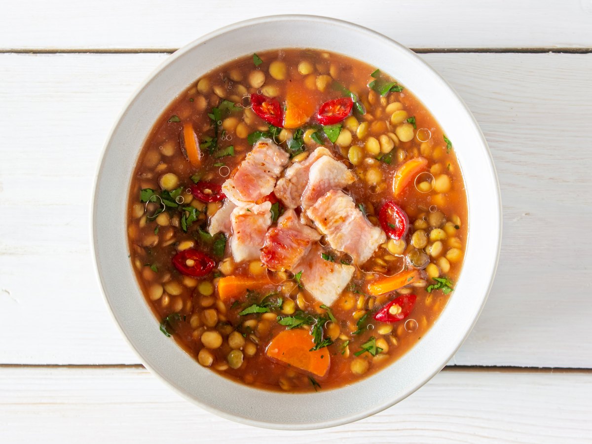 Teller Linsensuppe mit Möhren und angebratenem Speck
