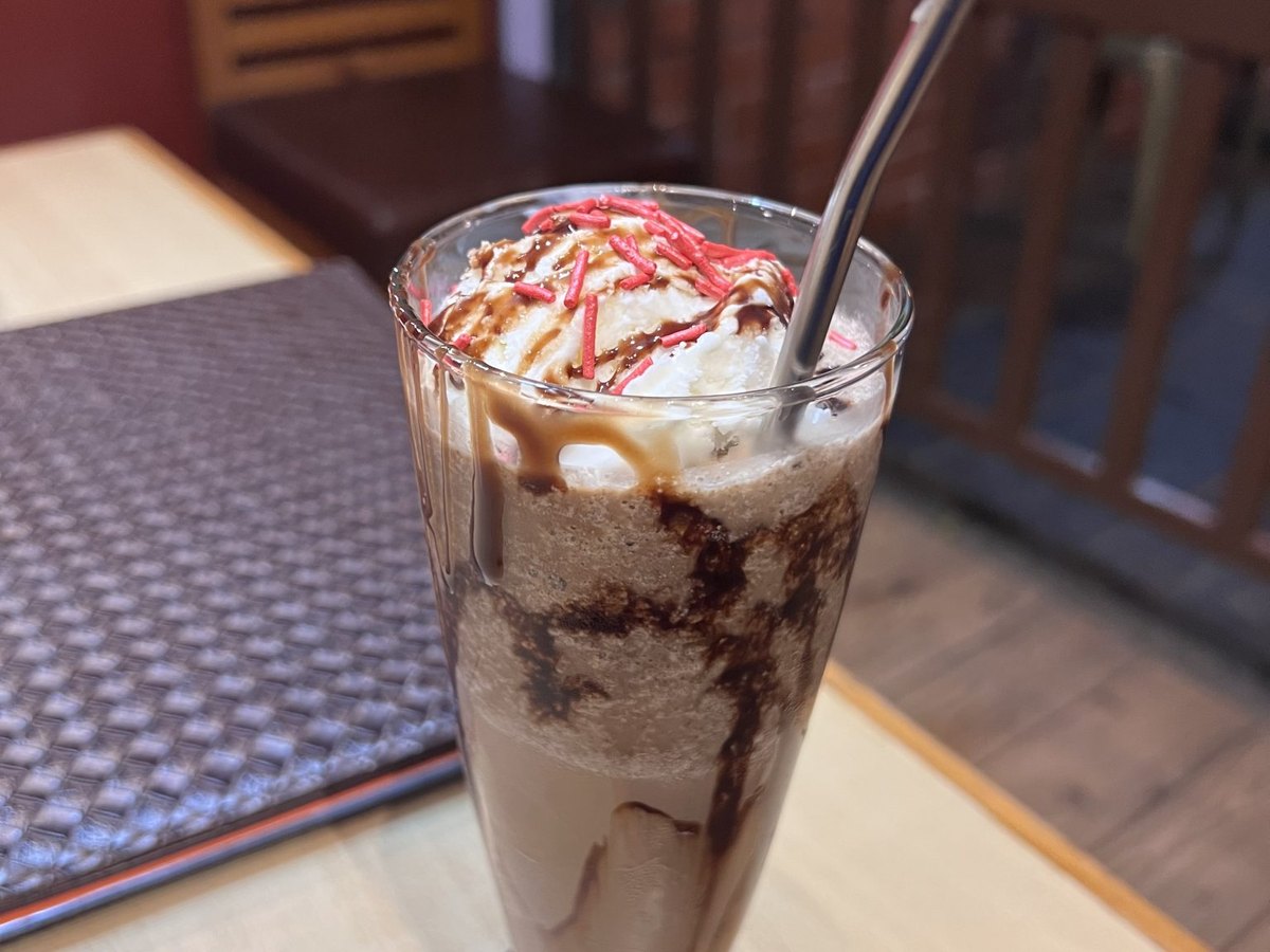 Milchshake im hohen Glas mit Sahne und Strohhalm