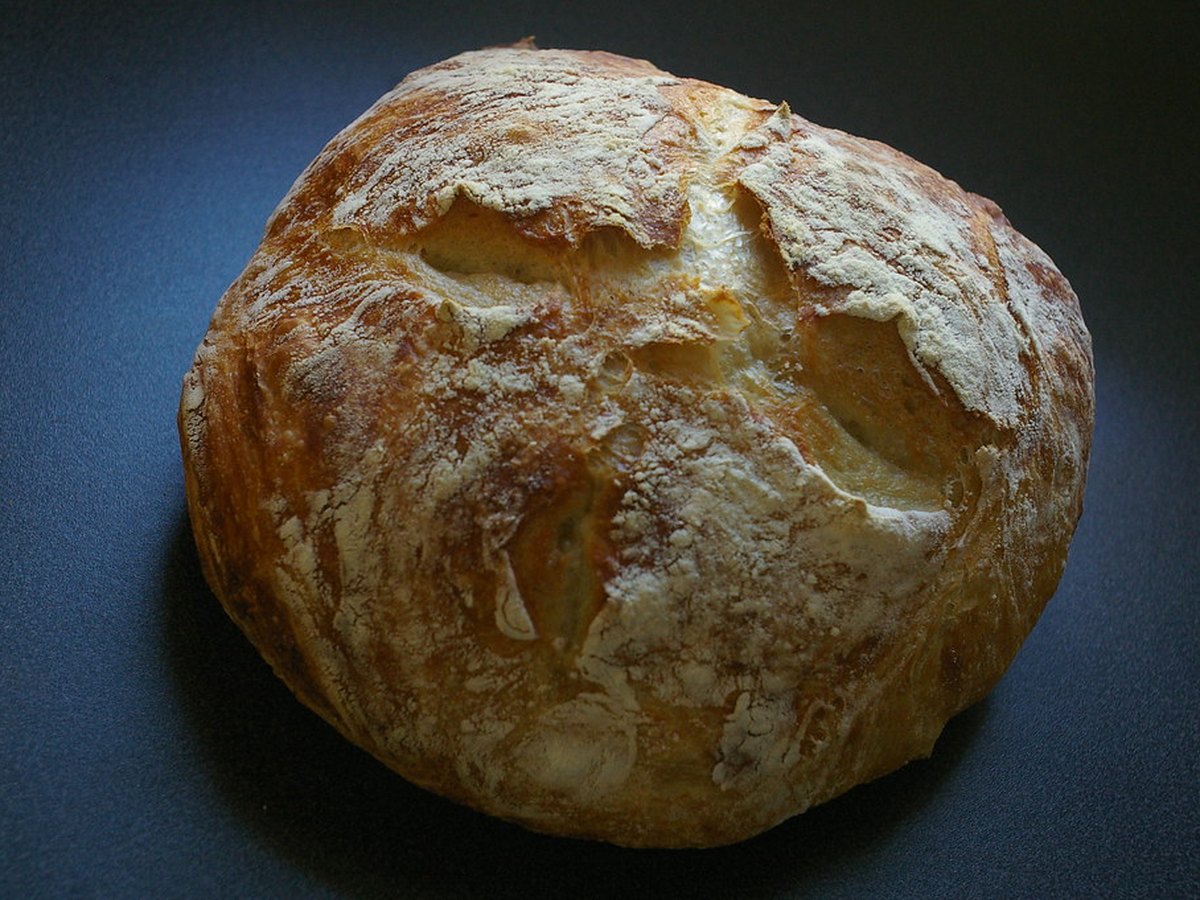 Rundes Bauernbrot mit dunkler Kruste auf einem Holzbrett