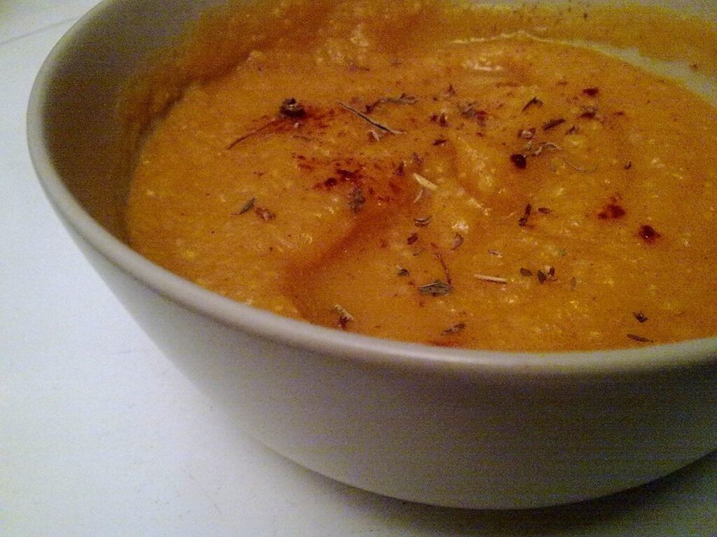 Orangefarbene Kürbissuppe mit Kürbiskernen und Sahne in einer Schale