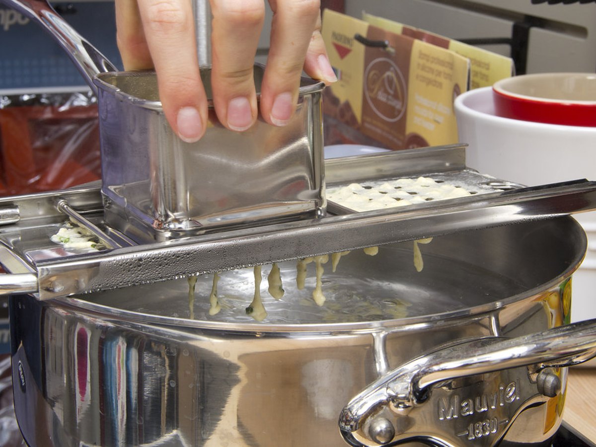 Teig wird durch den Knöpflehobel ins Wasser gerieben
