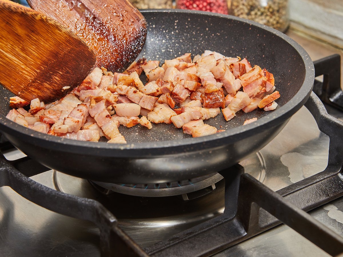 Speckwürfel werden mit Zwiebeln in der Pfanne gebraten