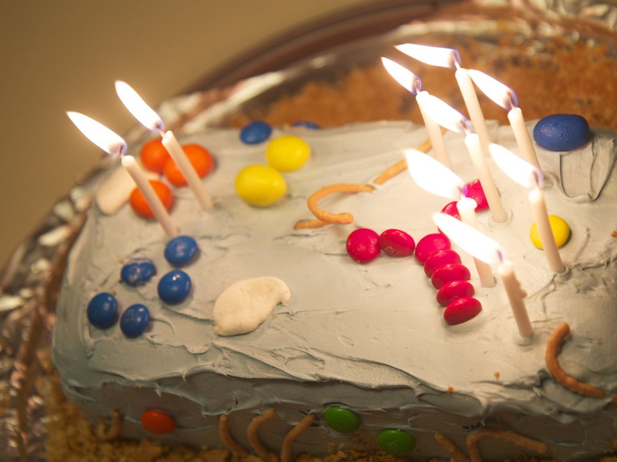 Bunte Streusel werden auf einen verzierten Kuchen gestreut