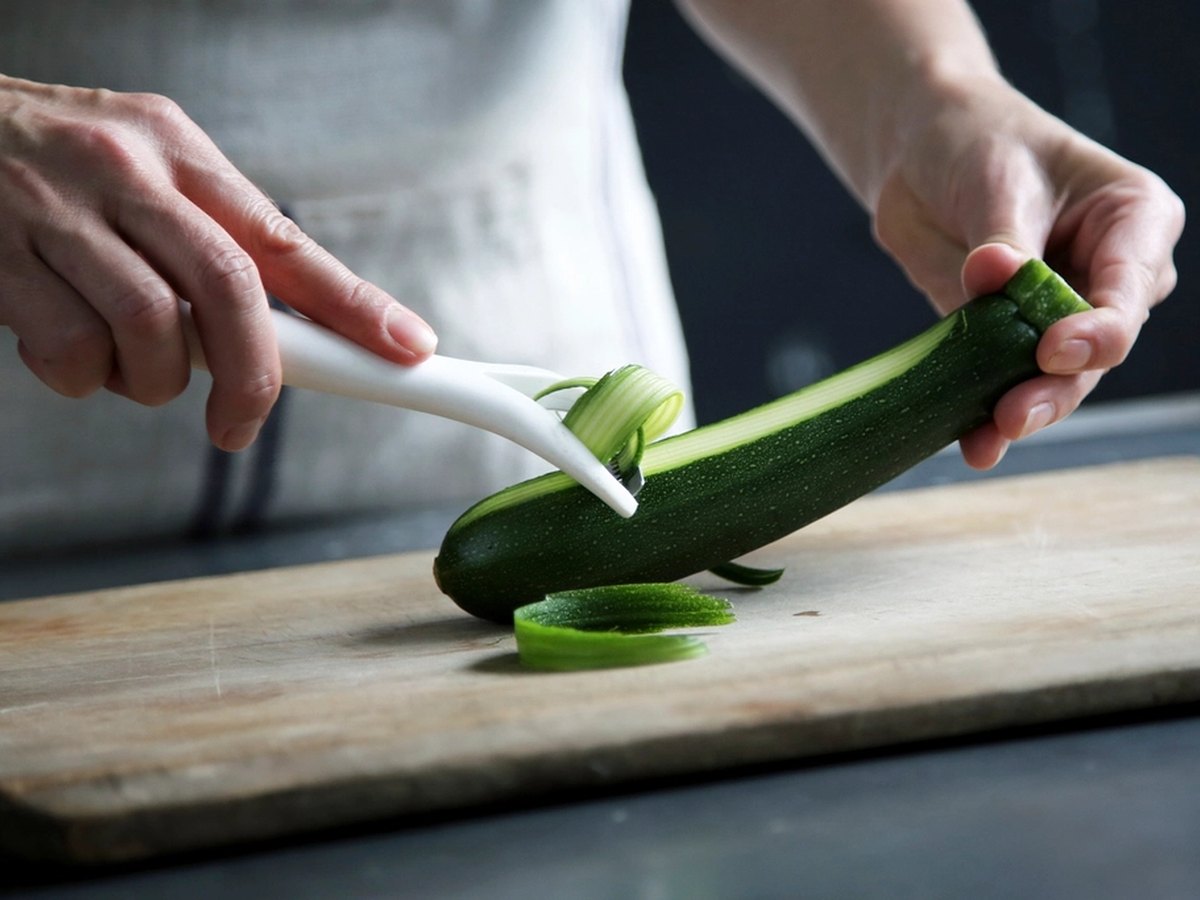 Zucchini wird auf einem Brett in Scheiben geschnitten