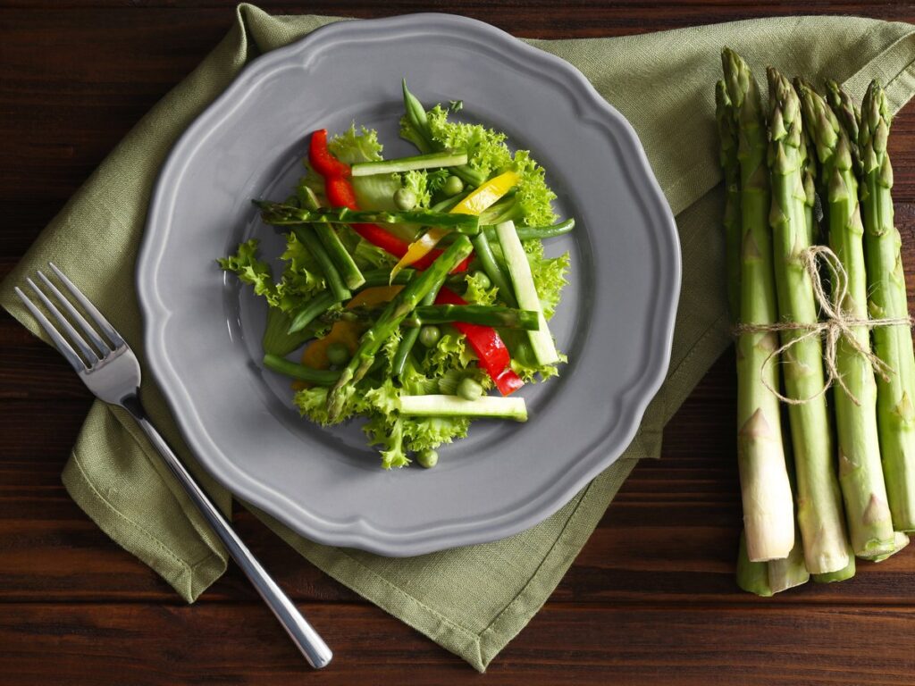 Spargelsalat mit grünem Spargel und Gemüse auf einem Teller