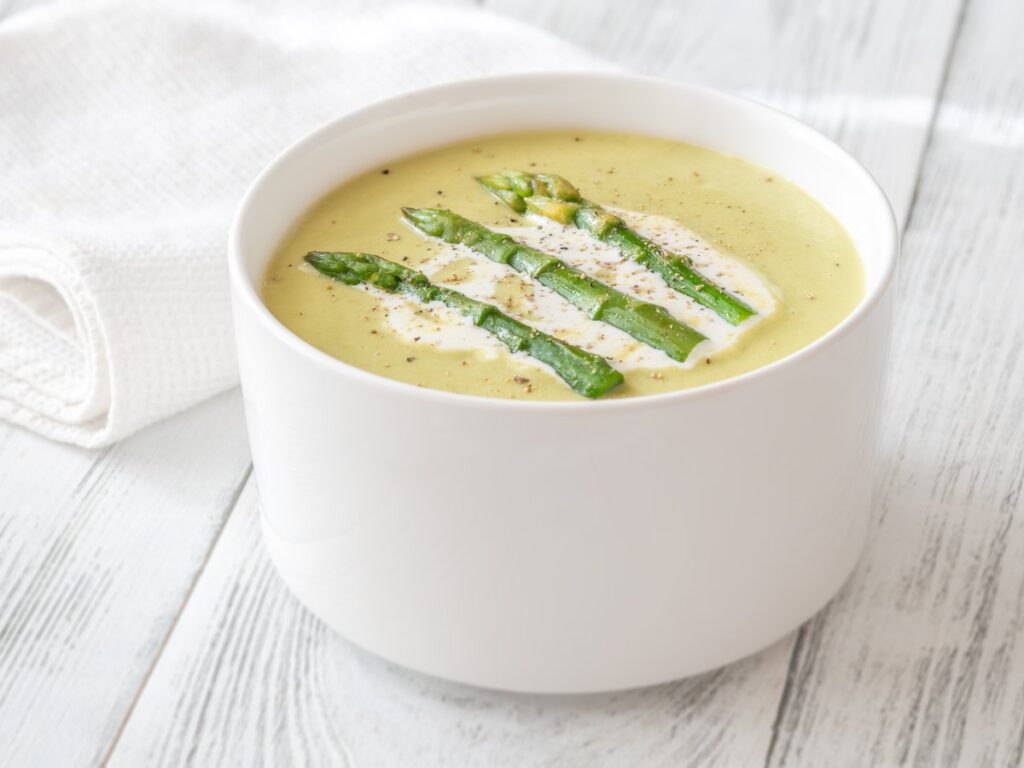 Cremige Spargelsuppe in weißer Schale mit Sahnespirale und Croûtons