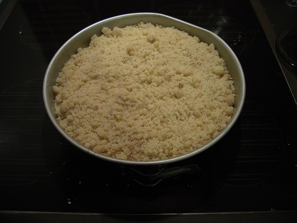Ein mit Streuseln bedeckter Kuchen in der Springform, bereit für den Ofen